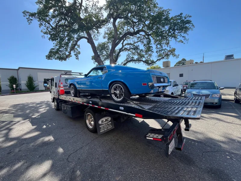 Classic blue Ford Mustang on a Mena's Towing flatbed